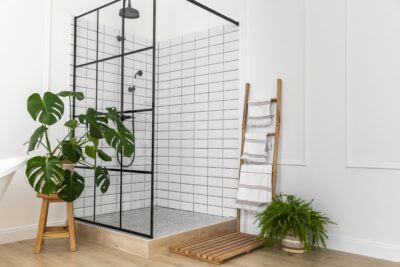 Modern bathroom with glass shower enclosure, indoor plants, and towel ladder.