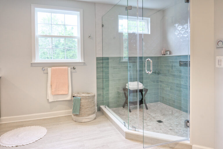 Modern bathroom with glass shower enclosure and green tile walls.
