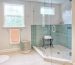 Modern bathroom with glass shower enclosure and green tile walls.